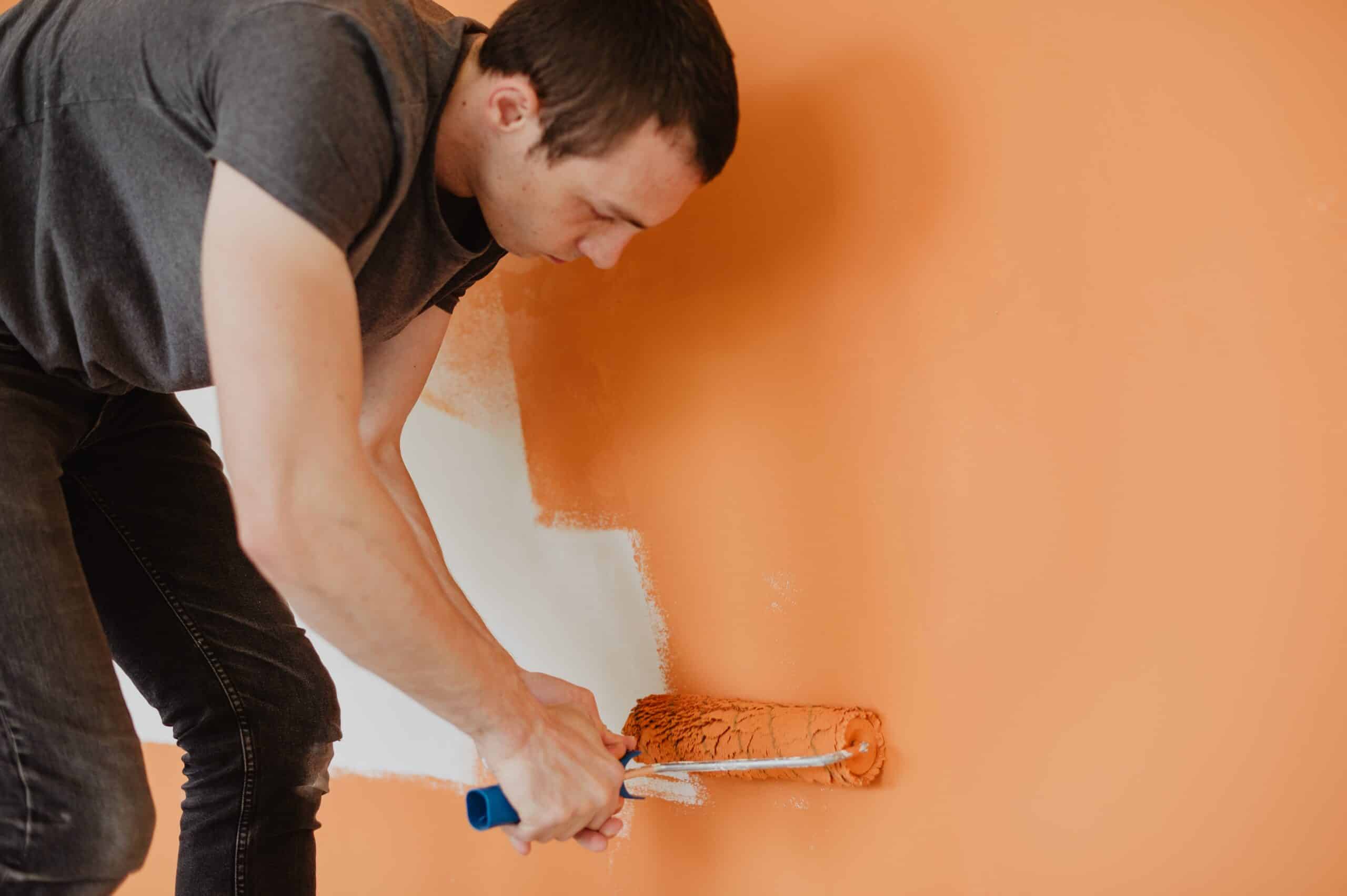 man painting with bright orange paint