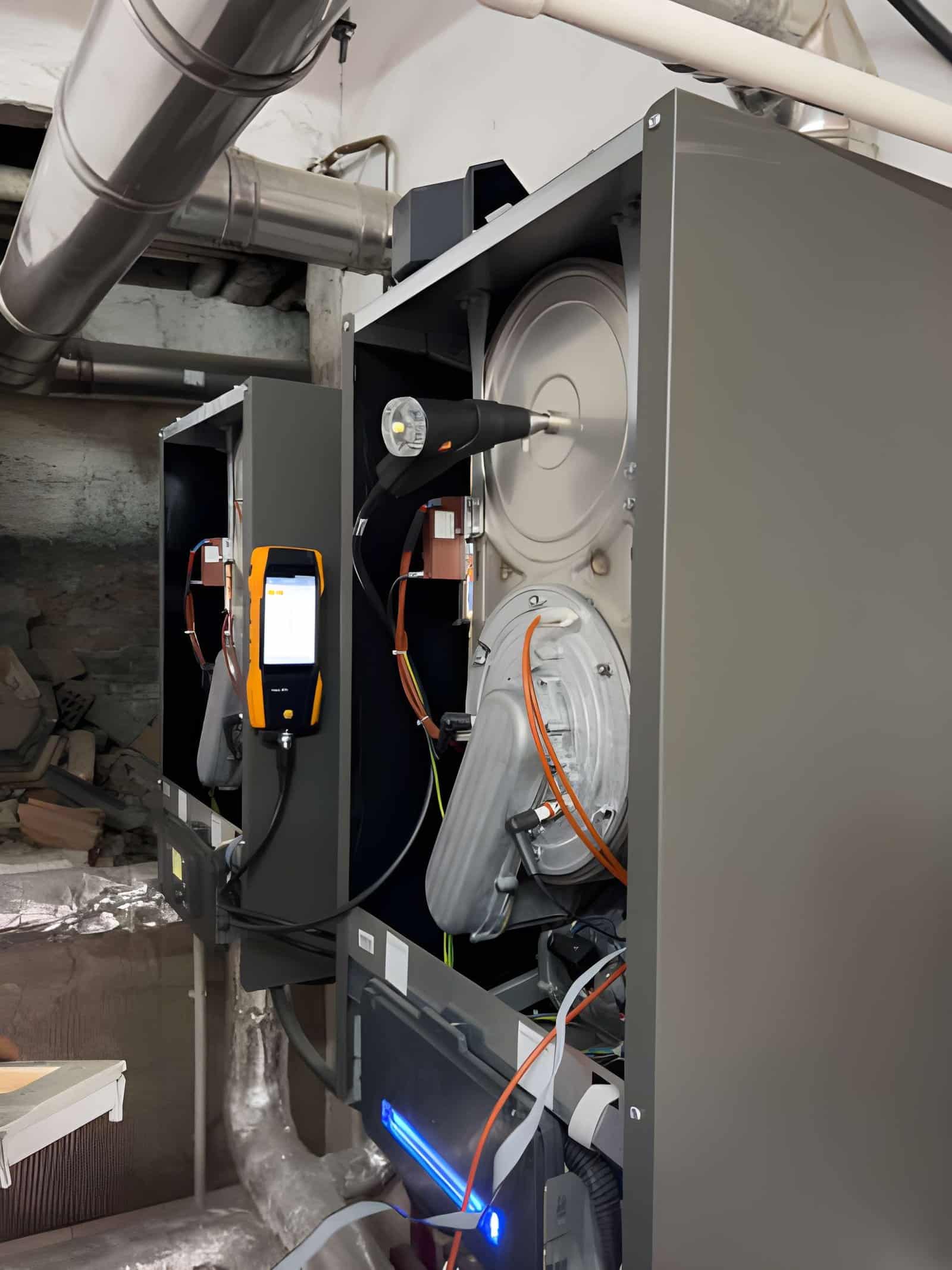 Repairman using tools to fix the blower motor inside an open gas furnace.