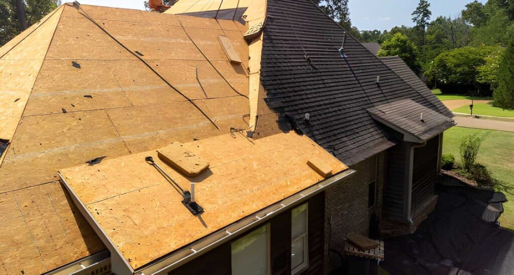 Roofing contractors inspecting roof damage before replacement
