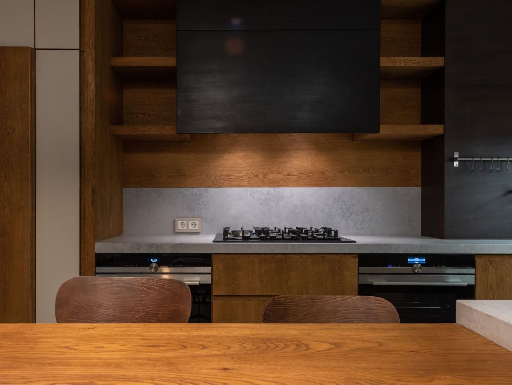 Warm honey-toned wood kitchen cabinets paired with a stone backsplash in a remodeled home