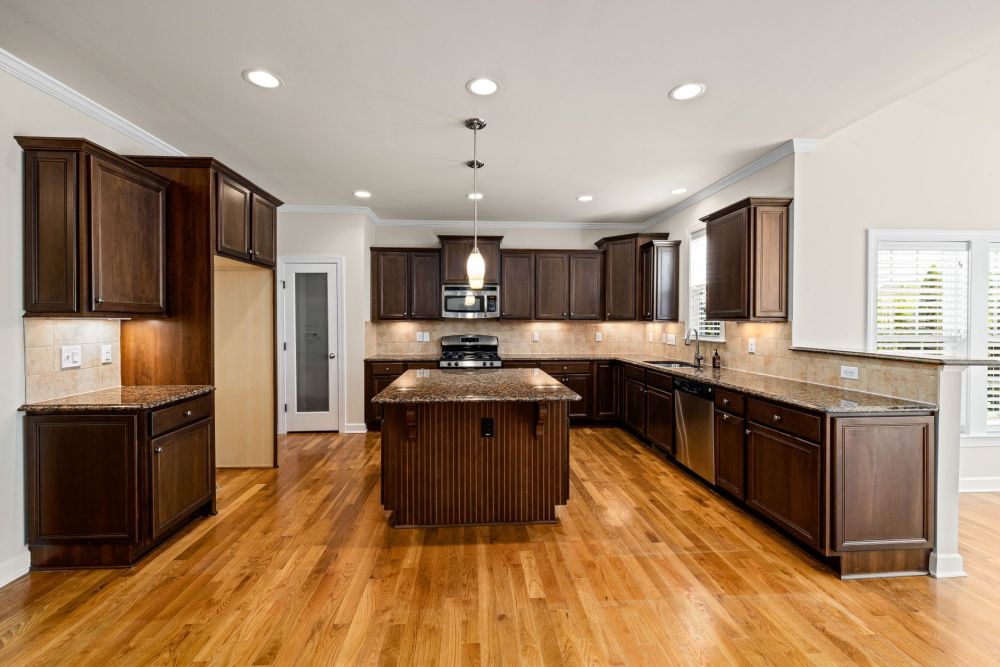 Deep green kitchen island with brass hardware in a contemporary remodeled home