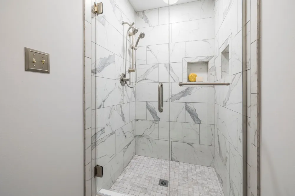 Contractor installing large-format tile in a walk-in shower during bathroom remodeling project