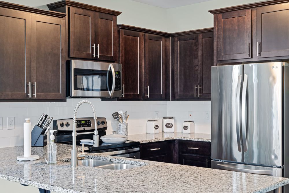 Dark granite countertop in outdated kitchen showing wear and fingerprint smudges