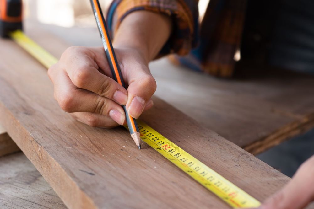 Remodeling contractor measuring kitchen cabinets during in-home estimate visit