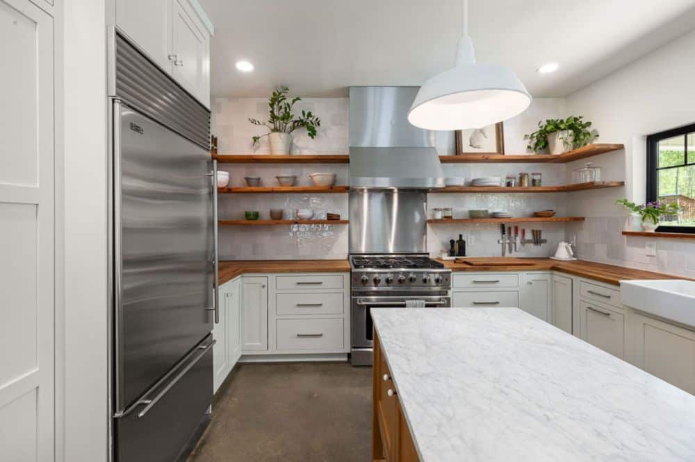 Open kitchen shelving replacing upper cabinets in a small renovated kitchen
