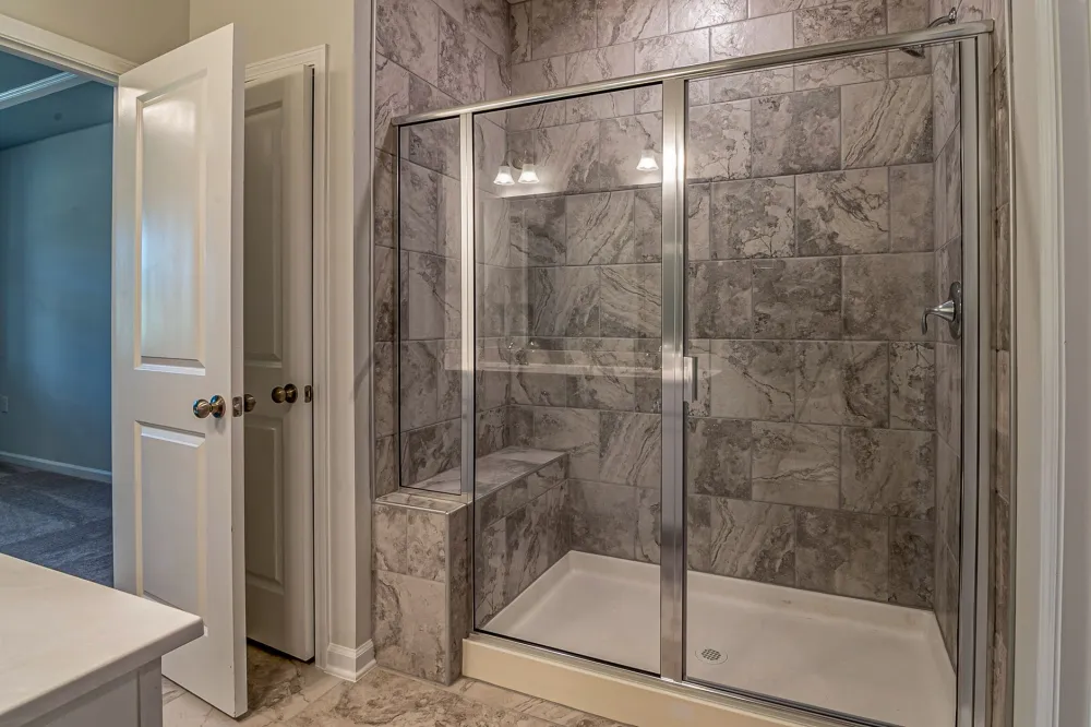 Contractor laying large format porcelain floor tile during a master bathroom renovation