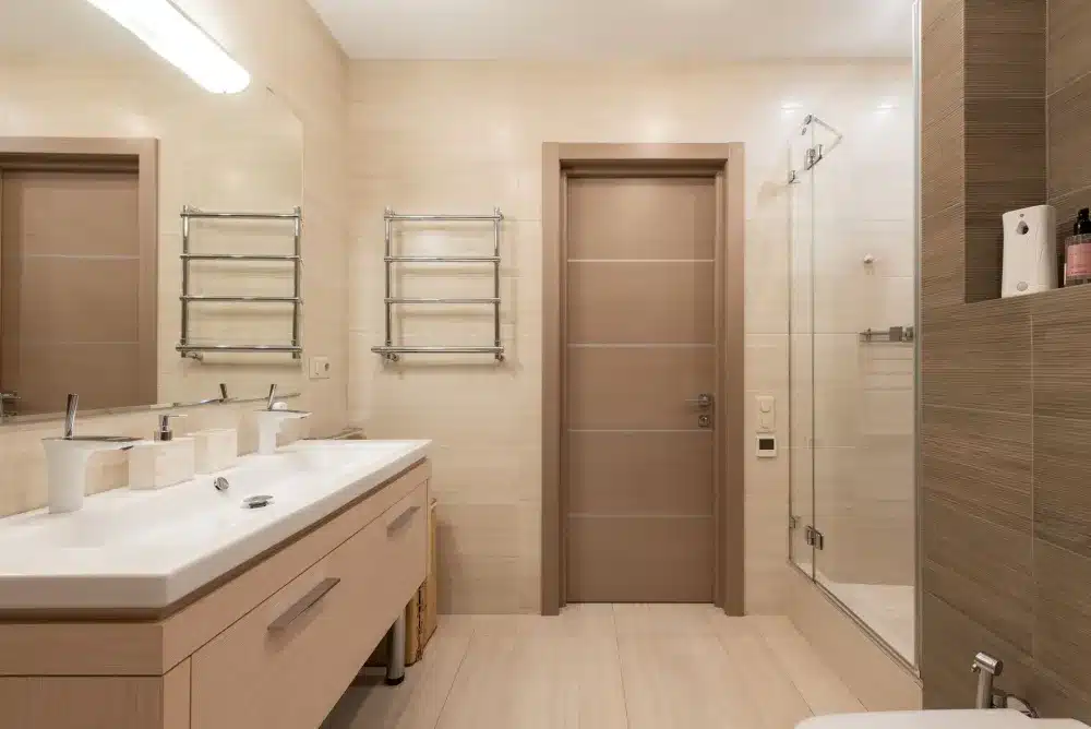Completed bathroom shower remodel with frameless glass enclosure and stone-look tile surround