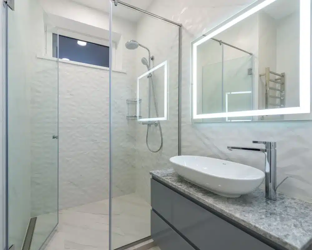 Walk-in shower with subway tile walls and frameless glass door in a remodeled bathroom