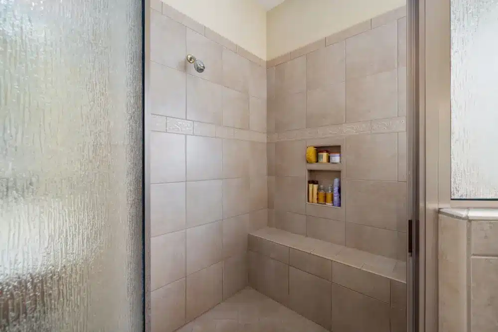 Built-in shower niche and bench with porcelain tile in a remodeled walk-in shower