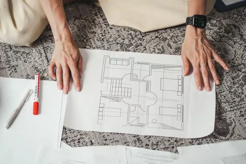 Homeowner reviewing kitchen remodel design plans with a contractor at a table