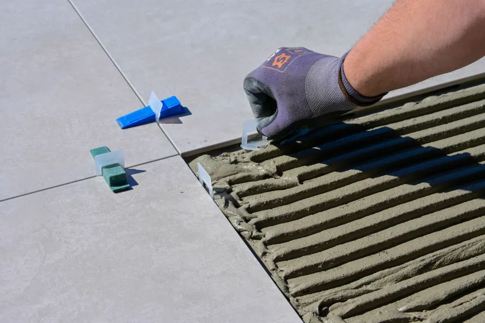 Installer laying an uncoupling membrane over a slab before setting bathroom tile